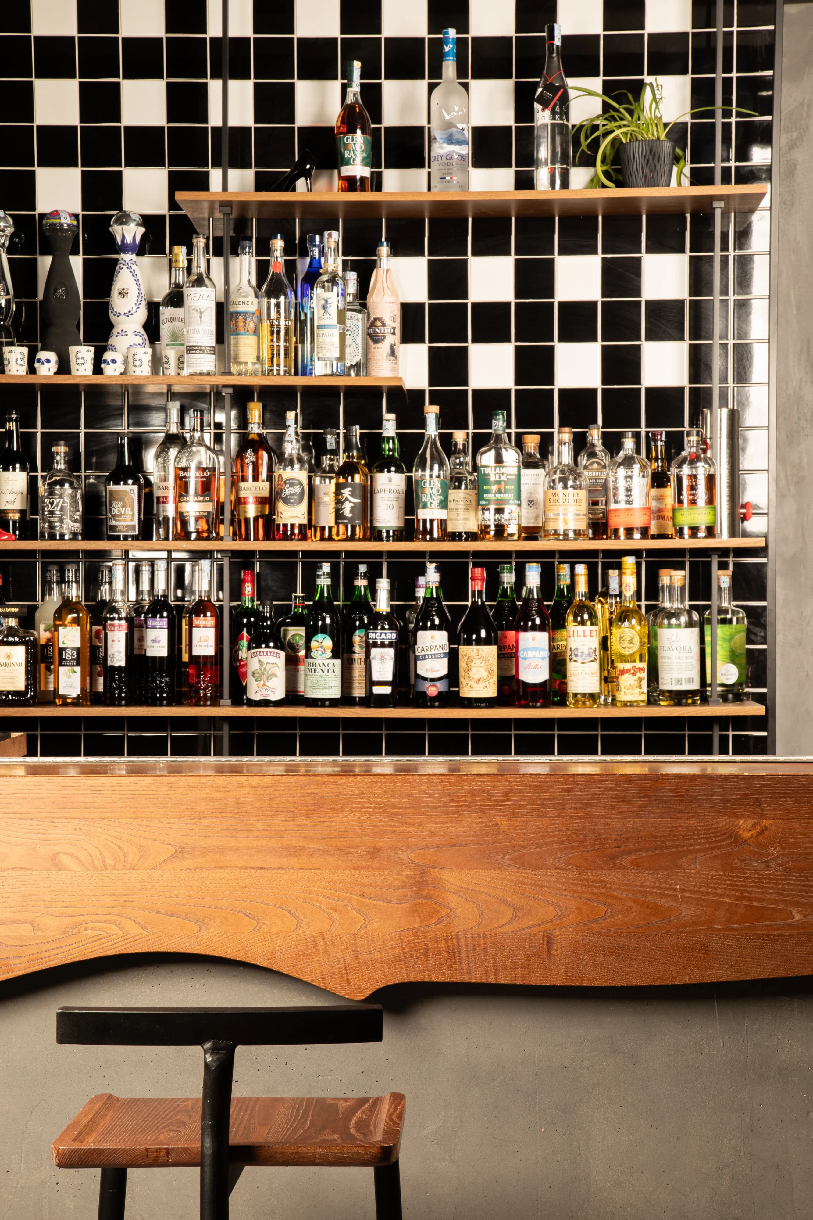 Bar shelves stocked with bottles against black and white tile
